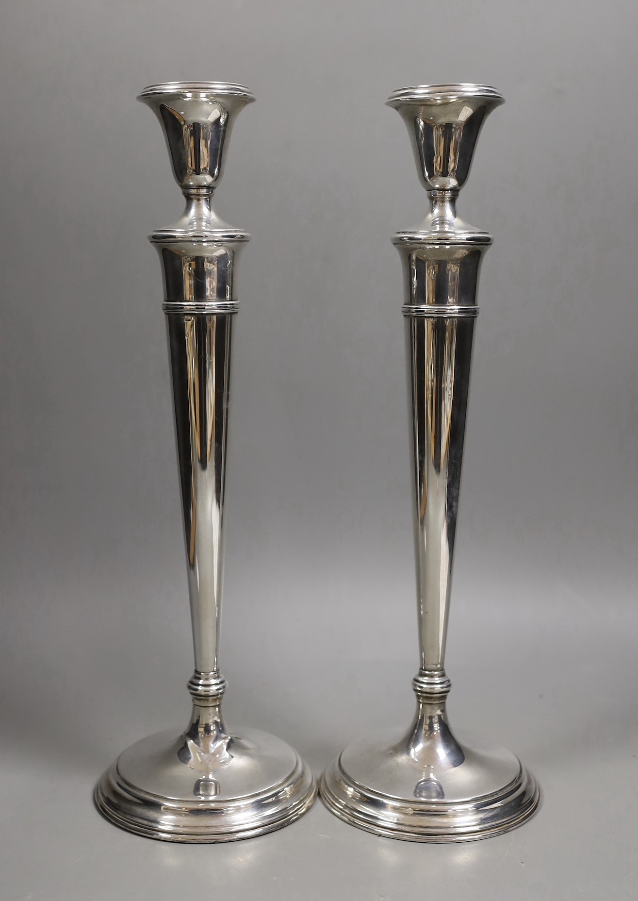 A pair of North American sterling candlesticks, with tapering stems, on circular bases, height 35.7cm, weighted.